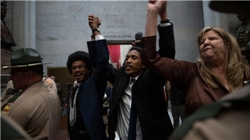Die demokratischen Abgeordneten Justin Pearson (v.l.), Justin Jones und Gloria Johnson halten ihre Hände hoch, als sie durch die Türen des Repräsentantenhauses im Tennessee State Capitol gehen.