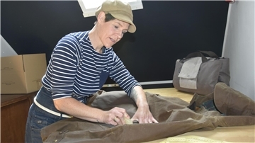 Die Designerin Jennifer Bujko zeigt, wie die Capes gewachst werden, damit sie keine Feuchtigkeit durchlassen.