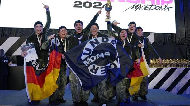 Eine Tanzgruppe schwenkt Fahnen und hält einen Siegerpokal in die Höhe.