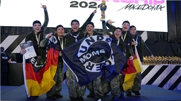 Eine Tanzgruppe schwenkt Fahnen und hält einen Siegerpokal in die Höhe.