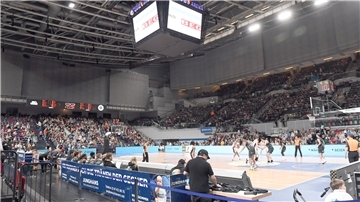 Basketballer beim Spieil in einer Arena.