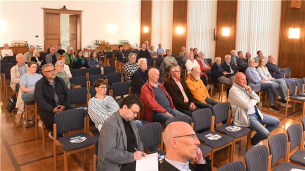 Menschen sitzen in einem Raum und hören zu.