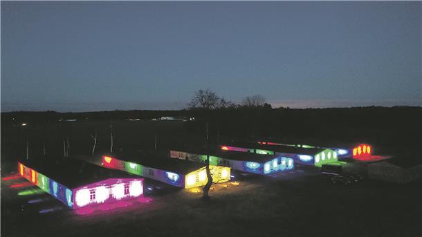 Die erhaltenen Holzbaracken auf dem Gelände der Sandbosteler Gedenkstätte wurden in Regenbogenfarben angestrahlt.