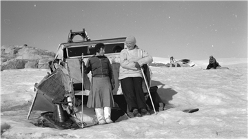 Die Ethnologin Aenne Schmücker zusammen mit ihrem Begleiter Joko auf Grönland vor einem von der Wegener-Expedition 1930/31 benutzten Motorschlitten.