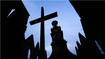 Ein großes Kreuz steht vor einer Kirche.