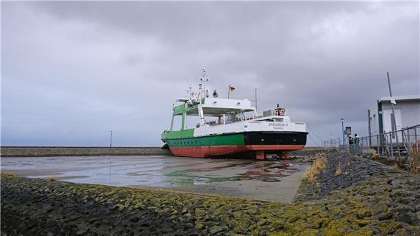 Schwimmkran hebt gestrandete Fähre ins Wasser Die Fähre „Spiekeroog IV“ wegen des Sturms über die Kaimauer geschoben worden und liegt nun auf einem Parkplatz am Fährterminal.