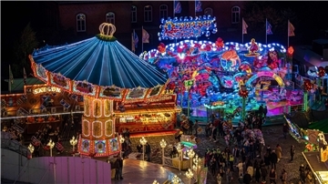 Die Fahrgeschäfte auf dem Freimarkt leuchten mit bunten Lichtern und Reklameschriftzügen.