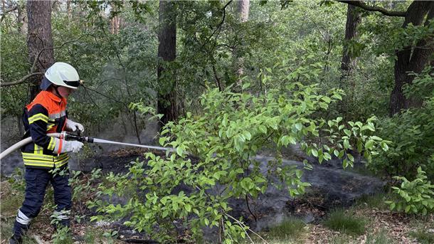 Ein Feuerwehrmann löscht einen Flächenbrand.