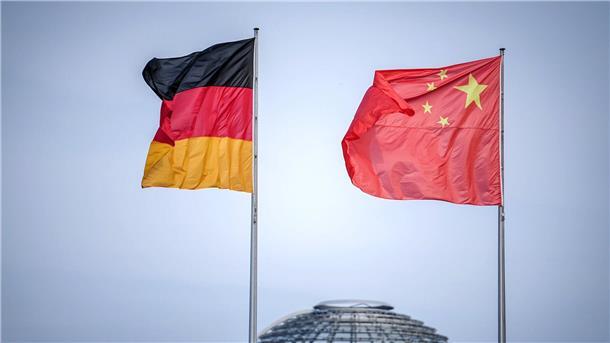 Die Flaggen von Deutschland und China wehen vor dem Bundeskanzleramt. Im Hintergrund die Kuppel des Reichstagsgebäudes.