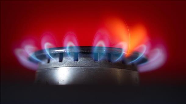 Die Flamme eines Gasherdes brennt in einer Küche.