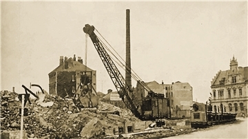 Ein Schwarz-Weiß-Foto aus dem Jahr 1944: Es zeigt einen Kran und einen Schuttberg. Dahinter und auch rechts im Bild stehen einzelne Häuser.