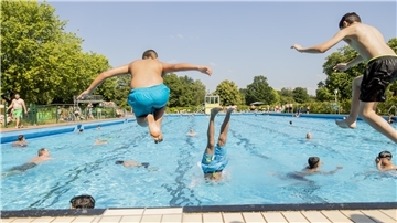 Jungs springen in das Badebecken. 