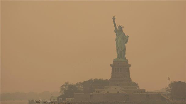 Die Freiheitsstatue ist in orangefarbenen Dunst gehüllt.