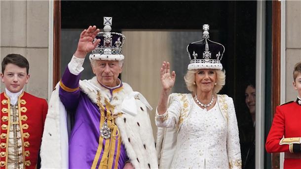 Tradition, Party und Protest: Charles und Camilla gekrönt Die frisch gekrönten König Charles III. und Königin Camilla winken vom Balkon des Buckingham Palastes der Menge zu.