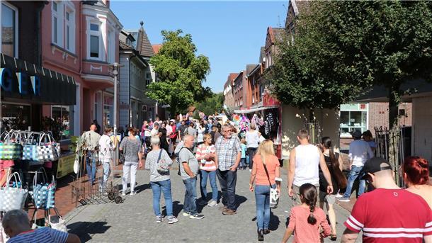 Kribbeln im Bauch beim Frühjahrsmarkt und Geschäfte versprechen Rabatte Menschen in sommerlicher Kleidung auf einer Straße
