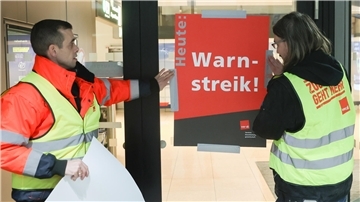 Airport-Mitarbeiter bringen zu Streikbeginn am Flughafen Hamburg ein Plakat mit der Aufschrift „Warnstreik“ an. 