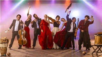 Musikerinnen und Musiker der Gruppe Los Tempramentos mit Instrumenten in buntem Scheinwerferlicht.