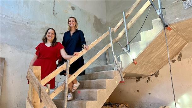 Zwei Frauen stehen im Rohbau auf einer Treppe
