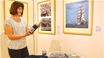 Die Historikerin Dr. Kerstin Ras-Dürschner hat an der Ausstellung zur Sail gearbeitet. Die Sektflasche, die sie in der Hand hält, wurde anlässlich derersten Sail angeboten.