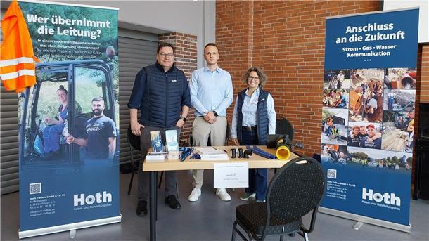 Drei Menschen bei einer Messe an einem Stand