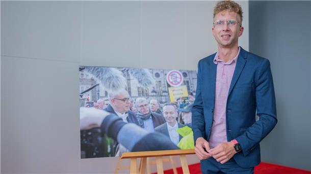 Das sind die Gewinner des Bremer Fotopreises 2023 Ein Mann steht vor einer Staffelei, auf der ein Foto zu sehen ist.
