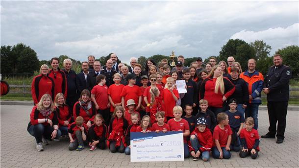 Kinder, Jugendliche und Erwachsene der Kinder- und Jugendfeuerwehr Lunestedt posieren zusammen mit ihren Gästen für ein Jubiläumsfoto 