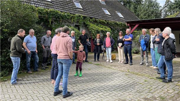 Menschen stehen im Halbkreis auf Hofeinfahrt