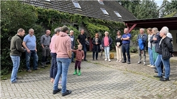 Menschen stehen im Halbkreis auf Hofeinfahrt