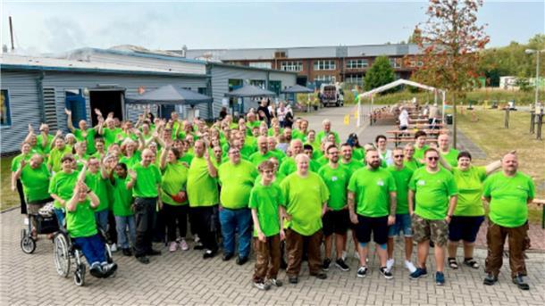 Gruppe in grünen T-Shirts auf einem Hof.