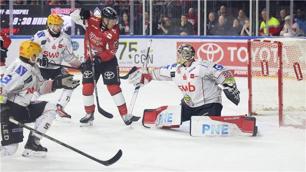 Ein Kölner Eishockeyspieler fälscht eine Scheibe vor dem Bremerhavener Tor ab.