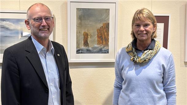 Ein Mann und eine Frau stehen vor einer Wand mit ausgestellten Bildern