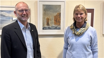 Ein Mann und eine Frau stehen vor einer Wand mit ausgestellten Bildern