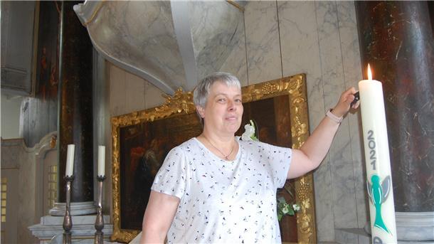 Eine Frau entzündet eine Kerze.