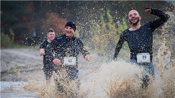 Drei Männer rennen durch Wasser.