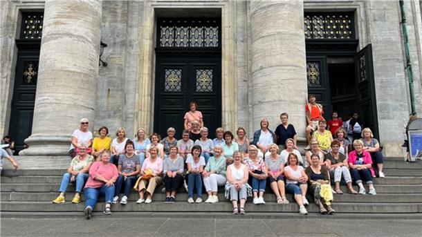 Die Zevener Landfrauen  sitzen auf der Treppe eines historischen Gebäudes.