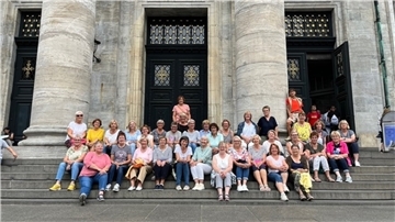 Die Zevener Landfrauen  sitzen auf der Treppe eines historischen Gebäudes.