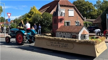 Ein Anhänger mit dem Modell einer Kirche, der von einem Trecker gezogen wird.