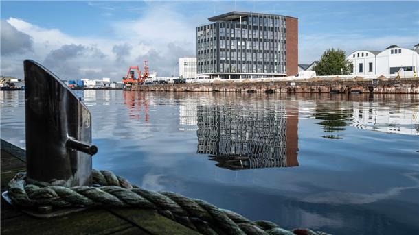 Am Eingang zum Werftquartier: Lichtdurchflutete Arbeitsplätze im Fischereihafen Die lichtoffene Glasfassade lässt den Bau trotz seines Volumens von außen betrachtet leicht erscheinen.