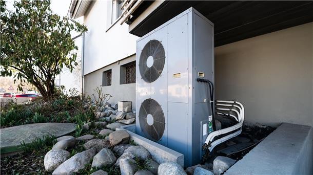 Die Lüftungsanlage einer Wärmepumpe steht vor einem Wohnhaus.