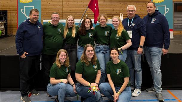 Gruppenfoto von sieben jungen Frauen und vier Männern in einer Turnhalle