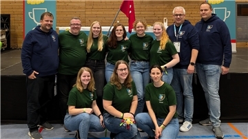 Gruppenfoto von sieben jungen Frauen und vier Männern in einer Turnhalle