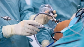 Ein Arzt operiert einen Patienten am Knie.