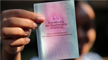 Jemand hält einen Ausweis in die Kamera. 