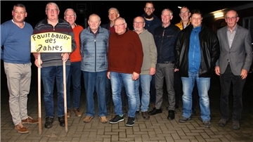 Zwölf Männer stehen in einer Reihe. Eine hält ein Schild mit der Aufschrift „Faustballer des Jahres“. 