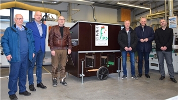 Männergruppe neben einem mobilen Hühnerstall.