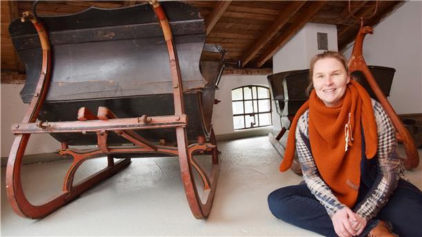 Die Museumsleiterin der Moorseer Mühle hat die Dauerausstellung überarbeitet. Sie sitzt vor zwei Kutschen, die früher während des Winters für Sonntagsausflüge genutzt wurden.