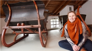 Die Museumsleiterin der Moorseer Mühle hat die Dauerausstellung überarbeitet. Sie sitzt vor zwei Kutschen, die früher während des Winters für Sonntagsausflüge genutzt wurden.