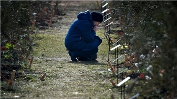 Die Mutter eines russischen Soldaten, der bei einer Militäraktion in der Ukraine getötet wurde, kniet neben einem Baum, der zum Gedenken an ihren Sohn in der Allee der Helden in Sewastopol auf der Krim gepflanzt wurde.