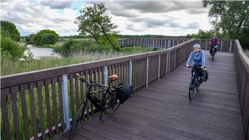 Mehrere Radfahrer fahren über die neue Brücke an der Geeste.