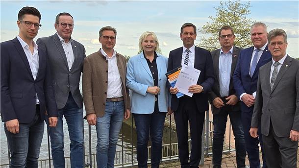 Sieben Männer und eine Frau stehen nebeneinander.